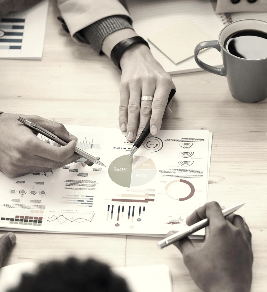 Perspectiva cenital de una mesa de trabajo con personas contrastando ideas